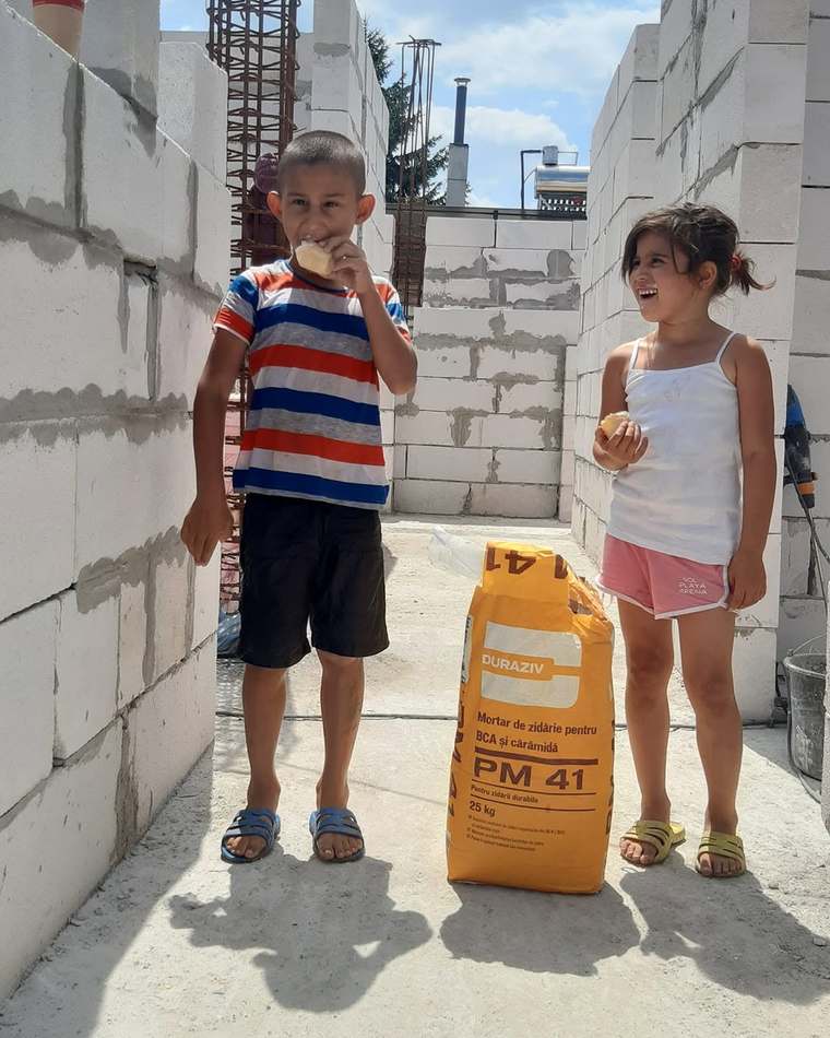 Doi copii ai familiei Manea, la o gustare între zidurile de BCA ale casei noi